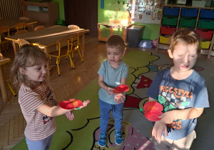 Zdjęcie przedstawia Alę, Szymona i Maksia z grupy I podczas zabawy ruchowej połączonej z ćwiczeniami artykulacyjnymi.
