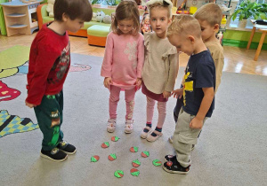 Zdjęcie przedstawia pięcioro dzieci z grupy III podczas ćwiczeń słuchowych - dzielnie słów na sylaby.