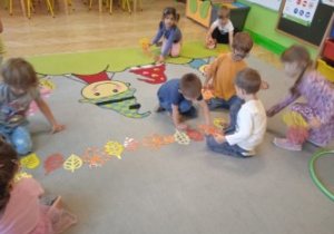 Na tym zdjęciu widać dzieci układające liśce według określonego rytmu.