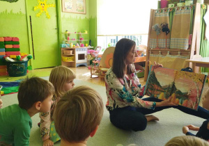 Na tym zdjęciu widać mamę Kuby, która czyta książkę oraz dzieci wsłuchane w jej treść.