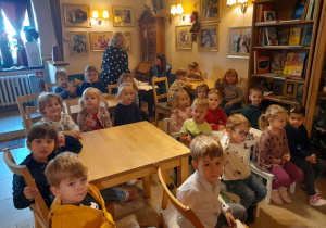 Zdjęcie przedstawia dzieci z grupy "Krasnali" przy stolikach w kawiarence.
