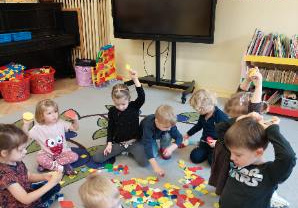 Zdjęcie przedstawia dzieci z grupy I i II podczas zabawy z figurami geometrycznymi.