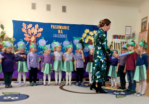 Zdjęcie przedstawia dzieci oraz panią Dyrektor, która magicznym ołówkiem pasuje kolejne dziecko na przedszkolaka.