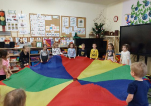 Zdjęcie przedstawia dzieci podczas zabaw z chustą animacyjną utrwalających kolory.
