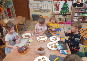 Zdjęcie przedstawia dzieci: Maję, Olę, Filipa i Stasia ozdabiających ciasteczka.
