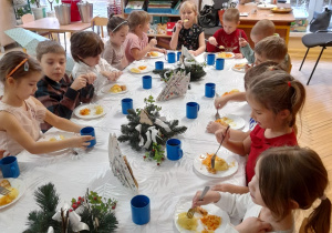 Zdjęcie przedstawia dzieci z grupy III przy wspólnym, świątecznie zastawionym stole.