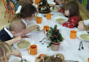 Zdjęcie przedstawia dzieci przy wspólnym, świątecznie zastawionym stole.