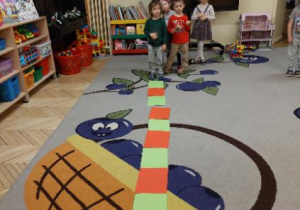 Zdjęcie przedstawia dzieci z grupy II podczas układania rytmów złożonych z dwóch kolorów.