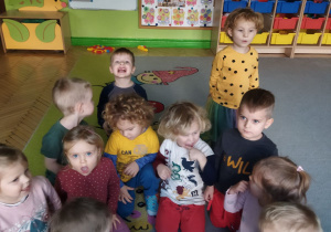 Zdjęcie przedstawia dzieci z grupy I podczas zabawy z kostką - wykonywanie ćwiczeń, jakie zostały przypisane do danej liczby oczek na kostce.