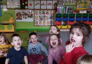 Zdjęcie przedstawia dzieci z grupy II podczas wykonywania ćwiczeń narządów mowy.