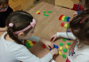 Zdjęcie przedstawia dzieci z grupy II manipulujące kolorową mozaiką.