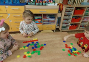 Zdjęcie przedstawia dzieci z grupy II manipulujące kolorową mozaiką.