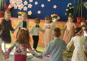 Zdjęcie przedstawia dzieci podczas wykonywania układu tanecznego.