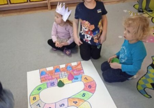 Zdjęcie przedstawia dzieci z grupy I i II grające w grę planszową.