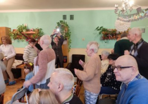 Zdjęcie przedstawia seniorów oglądających przedstawienie.