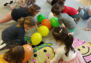 Zdjęcie przedstawia dziec i z grupy II podczas zabawy oddechowej "Wesołe baloniki".