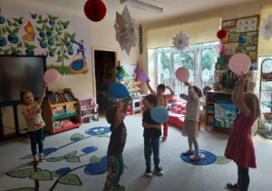 Zdjęcie przedstawia dzieci z grupy II podczas zabawy z balonami utrwalającej stosunki przestrzenne.