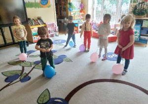 Zdjęcie przedstawia dzieci z grupy II podczas zabawy z balonami utrwalającej stosunki przestrzenne.