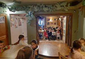 Zdjęcie przedstawia wnętrze kawiarenki oraz dzieci siedzące przy stolikach.