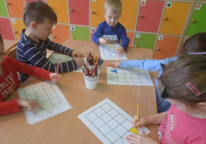 Zdjęcie przedstawia dzieci z grupy I i II kolorujące elementy na planszy do gry.