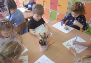 Zdjęcie przedstawia dzieci z grupy I i II kolorujące elementy na planszy do gry.