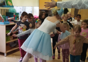 Zdjęcie przedstawia baletnicę i dzieci próbujące swoich sił w balecie.