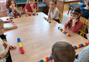 Zdjęcie przedstawia dzieci zgrupy II podczas układania kodu matematycznego z kolorowych klocków.