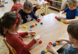 Zdjęcie przedstawia dzieci układające kod matematyczny z kolorowych klocków.