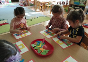 Zdjęcie przedstawia dzieci podczas zabaw z figurami geometrycznymi.