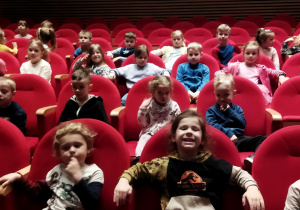 Zdjęcie przedstawia dzieci siedzące na widowni w teatrze.