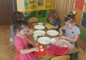 Zdjęcie przedstawia dzieci przekrawające jajka na pół.