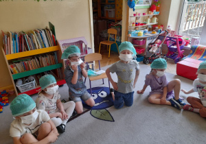 Zdjęcie przedstawia dzieci, które założyły czepki i maseczki obowiązujące na bloku operacyjnym.