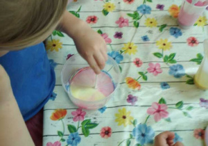 Na tym zdjęciu widać dziewczynkę mieszającą barwnik z mlekiem.