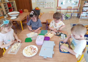 Na tym zdjęciu widać dzieci, które kroją w kostkę ser i pierś z kurczka.