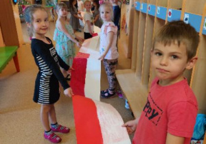 Na tym zdjęciu widać dzieci, które pokazują fragment flagi grupy III.