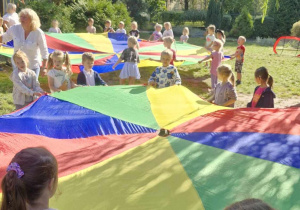 Zdjęcie przedstawia dzieci podczas kolejnych zabaw z chustą animacyjną.