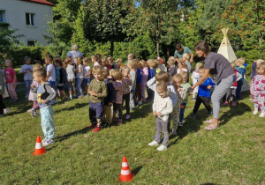 Zdjęcie przedstawia dzieci podczas wykonywania konkurencji sportowych.