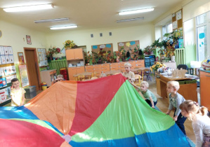 Zdjęcie przedstawia dzieci podczas zabawy z chustą animacyjną "Kolorowa chusta".