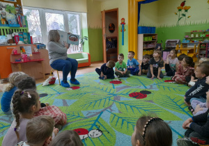 Na tym zdjęciu widać dzieci oraz panią bibliotekarkę czytającą bajkę.