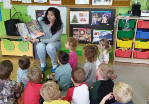 Na tym zdjęciu widać panią bibliotekarkę czytającą dzieciom bajkę.