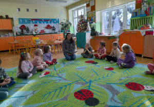 Na zdjęciu widać dziewczynki słuchające opowiadania czytanego przez mamę Helenki.