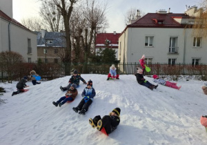 Na tym zdjęciu widać dzieci zjeżdżające z gorki na jabłuszkach.