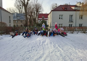 Zdjęcie przedstawia dzieci siedzące na jabłuszkach na górce.