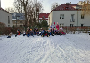 Zdjecie przedstwia dzieci na szczycie górki przygotowujące się do zjazdu.