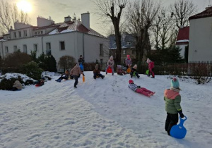 Zdjęcie przedstawia dzieci bawiące się na śniegu.