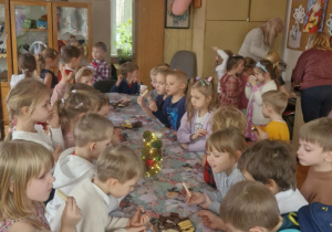 Zdjęcie przedstawia dzieci przy stole ze słodkim poczęstunkiem.