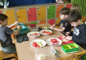 Zdjecie przedstawia Maję z grupy IV oraz Tymka i Julka z grupy III krojących produkty w grubą kostkę.