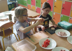 Zdjęcie przedstawia Maję i Oliwię z gruby IV krojące produkty w grubą kostkę.