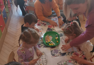 Na tym zdjęciu widać dzieci wykonujące pracę plastyczną oraz rodziców.