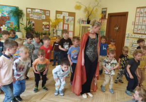 Na tym zdjęciu widać dzieci, które wraz z tancerką wykonują układ baletowy.